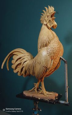 a wooden sculpture of a rooster on a stand