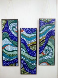 three pieces of art hanging on the wall in front of a white wall with blue and green designs