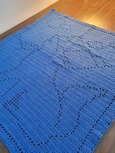 a blue crocheted blanket sitting on top of a wooden floor