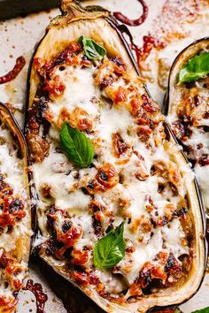 three stuffed eggplant boats on a baking sheet with cheese and basil garnish