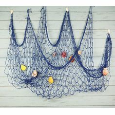 three blue net hanging on the side of a white wall with shells and seashells attached to it