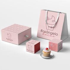 a cupcake with icing on it sitting next to two boxes and a paper bag