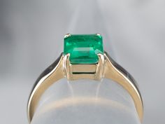 The mounting of this ring is vintage, crafted of a perfect, 18 karat yellow gold. We've set it with a gorgeous emerald that looks amazing surrounded by the bright polish of the prongs! Shades of green simply gleam from this gorgeous ring!Metal: 18K Yellow Gold Gem: Emerald 1.295 CaratsGem Measurements: 6.9 x 6.3 mm, Emerald Cut Ring Size: 6.50Marks: “18K” Stamped on the inside band Classic Princess Cut Solitaire Emerald Ring, May Birthstone Princess Cut Emerald Ring In Yellow Gold, Yellow Gold Emerald Ring With Asscher Cut, Heirloom Emerald Solitaire Ring, Gia Certified Classic Princess Cut Emerald Ring, Heirloom Green Emerald Solitaire Ring, Classic Emerald Ring In Yellow Gold, Classic Solitaire Emerald Ring For May Birthstone, Classic Solitaire Emerald Ring, May Birthstone