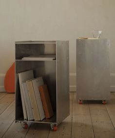 a metal book case sitting on top of a wooden floor next to an orange chair