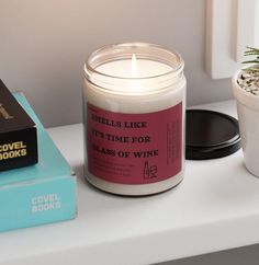 a candle sitting on top of a table next to a book and a potted plant