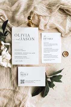 the wedding stationery is laid out on top of each other with flowers and greenery