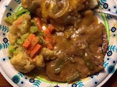 a white plate topped with meat covered in gravy and veggies