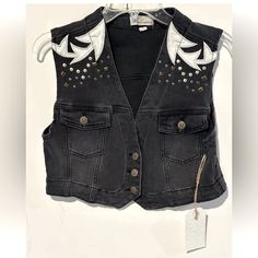 This Austin Landing Vest Is A Must-Have For Any Fashion-Forward Woman. The Black Denim And Leather Patches Give It A Edgy, Yet Chic Look That Is Perfect For Any Occasion. With A Button Closure And Studded Accents, This Vest Is Both Stylish And Functional. It Is Made Of A Cotton Blend Fabric And Lined With 100% Cotton, Making It Comfortable And Easy To Care For. This Vest Is Perfect For Summer, Fall, And Spring, And Is Available In A Women's Size L. The Biker Style And Cowboy/90s Theme Add A Touc Edgy Streetwear Vest For Spring, Edgy Denim Vest For Fall Streetwear, Spring Black Denim Vest, Black Sleeveless Denim Vest For Spring, Spring Biker Vest In Black, Summer Black Denim Vest For Streetwear, Spring Black Biker Vest, Edgy Sleeveless Denim Vest For Fall, Black Punk Vest For Spring