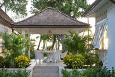 a gazebo in the middle of a garden with tables and chairs set up under it