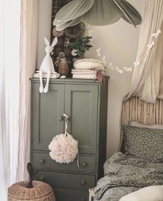 a green cabinet sitting in the corner of a bedroom next to a bed and pillows