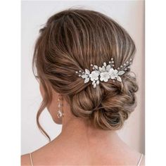 a woman wearing a wedding hair comb with flowers on the side and pearls in her hair