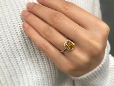 a woman's hand with a yellow and white diamond ring