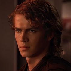 a close up of a person wearing a brown shirt and looking into the distance with blue eyes