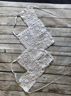 two white crocheted squares sitting on top of a wooden table