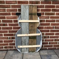 a wooden guitar hanging on the side of a brick wall