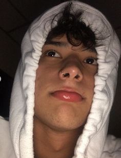 a man in a white hoodie with his face covered by a towel and nose piercing