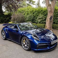 a blue sports car parked in front of a tree