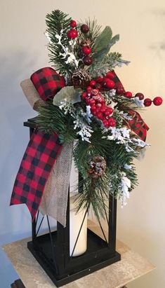 a christmas centerpiece with red berries, pine cones and greenery