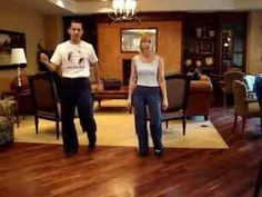 a man and woman standing next to each other in a living room filled with furniture