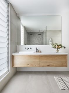 a bathroom with a large mirror above the sink and wooden cabinetry on the wall