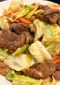 beef and lettuce stir fry with carrots on a white plate, ready to be eaten