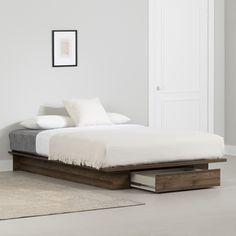 a bed sitting in the middle of a room next to a white wall and floor