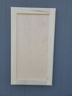 a wooden frame hanging on the side of a building with blue paint and white trim