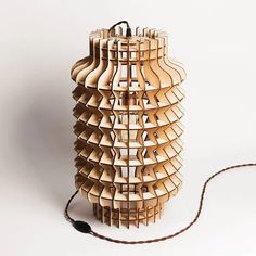 a lamp made out of wooden strips and strings on a white surface with a cord