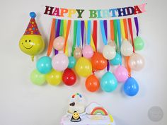 a birthday party with balloons, cake and streamers hanging on the wall next to it