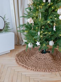 a small christmas tree in a room with wooden flooring and white ornaments on it