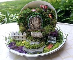 a plate that has some plants and rocks on it with a small house in the middle