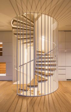 a spiral staircase in the middle of a room with wooden floors and white railings