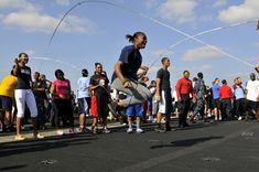 a group of people standing on the side of a road watching a skateboarder do a trick