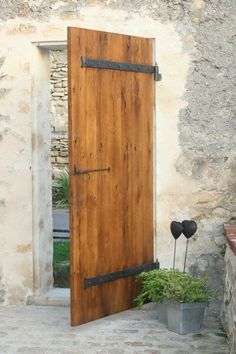 an open wooden door sitting next to a potted plant on the side of a building