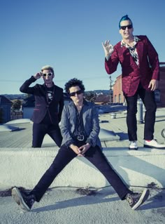 three men are posing for a photo on top of a roof with their hands in the air