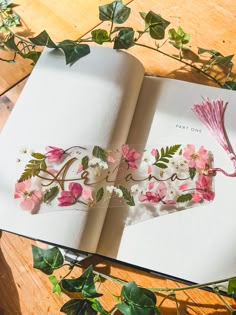 an open book with flowers and leaves on the pages that spell out'love '