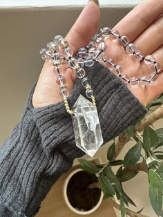 This stunning Clear Quartz Crystal Necklace is the perfect blend of elegance and spiritual energy. Featuring a striking, raw clear quartz point pendant, this necklace is hand-strung with clear quartz beads and gold-tone accents, adding a radiant touch to any outfit. The necklace is both a statement piece and a tool for spiritual healing, designed to amplify positive energies and promote mental clarity. Product Details: *Crystal: Natural Clear Quartz Point *Pendant Size: Approx. 5cm *Chain: Clear Quartz Beads with Gold-tone Spacer Beads *Chain Length: 21cm *Handmade with Love Properties of Clear Quartz: Clear Quartz is known as the "Master Healer," amplifying energy, thoughts, and the effects of other crystals. It is a highly prized stone for those looking to enhance their focus, clarity, a Clear Gemstone Beads Jewelry For Healing, Healing Clear Gemstone Beads Jewelry, Spiritual Crystal Necklaces With Gemstone Beads, Spiritual Round Beads Crystal Necklaces For Layering, Spiritual Crystal Necklace With Gemstone Beads, Spiritual Crystal Necklaces With Round Beads For Layering, Clear Gemstone Necklaces For Healing, Clear Crystal Gemstone Necklaces, Spiritual Crystal Necklaces For Healing