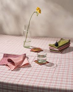 a table topped with plates and vases filled with flowers on top of a checkered table cloth