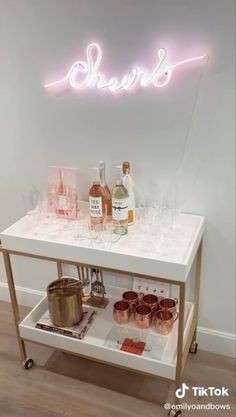 a bar cart with drinks on it in front of a neon sign that says sherb