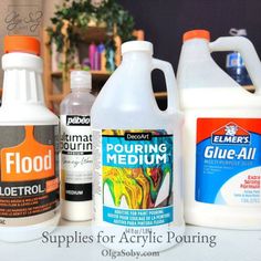 three gallon jugs of glue, one orange and one white are sitting next to each other on a table