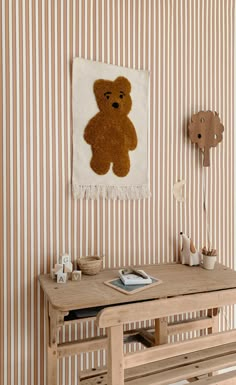 a teddy bear is hanging on the wall next to a wooden table with a phone