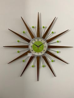 a clock that is on the wall and has green balls around it's sides