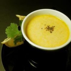 a white bowl filled with soup and garnished with cilantro on a black plate