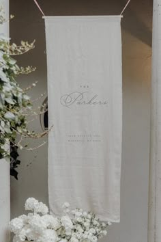 a white towel hanging from a clothes line next to flowers and a potted plant