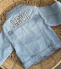 Hi there! Welcome to my shop. This listing is for the varsity font. These unisex personalized embroidered denim jacket are available in toddler and children's sizes. These Custom denim jacket makes the best birthday or baby shower gift!  Jacket is light wash and has a slightly oversized fit. Because these are one of a kind, returns are not accepted. Each item is made to order and hand embroidered by me so slight variations may occur. I am unable to replace/refund purchases based on color and fon Denim Blue Cotton Jacket With Letter Print, Casual Cotton Denim Jacket For College, Spring Cotton Denim Jacket For College, Long-sleeved Cotton Denim Jacket For College, Long Sleeve Cotton Denim Jacket For College, Cotton Long Sleeve Denim Jacket For College, Casual White Embroidered Denim Jacket, Casual Customizable Outerwear For Streetwear, School Spirit Cotton Outerwear