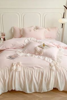 a bed with pink ruffled sheets and pillows