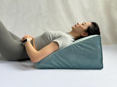 a woman laying on her stomach while holding a remote control