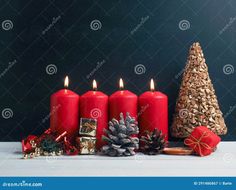 red candles with christmas decorations and pine cones