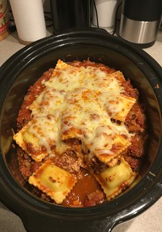 a crock pot filled with lasagna and cheese