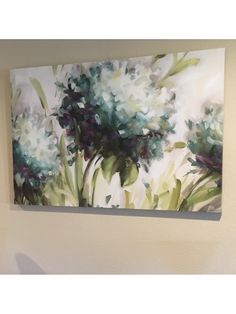 a painting hanging on the wall above a toilet in a room with white walls and blue flowers